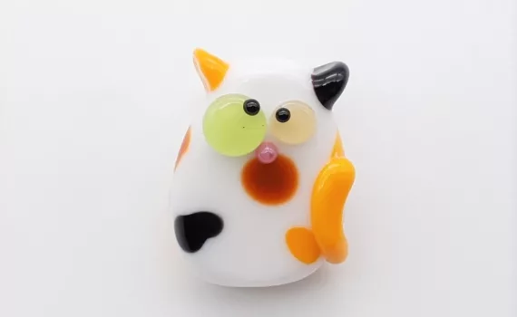 Lampwork glass bead kooky cat with a calico pattern.