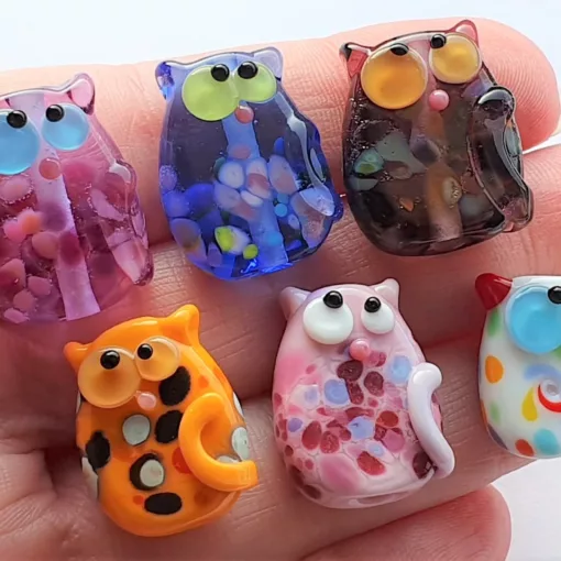 A collection of lampwork glass beads resembling cats, with frit, dots and swirls.