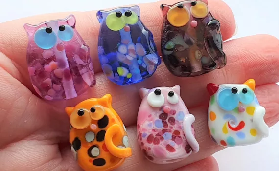 A collection of lampwork glass beads resembling cats, with frit, dots and swirls.